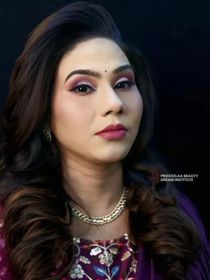 Celebrating defined curls and a glamorous makeup look. The voluminous hair is paired with a striking pink and purple eye, creating a look that is both bold and beautiful.