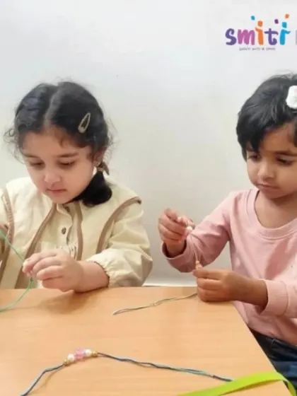 Two girls concentrate on threading beads to create handmade Rakhis. This Raksha Bandhan activity is a beautiful way for them to develop fine motor skills while making a gift of love.