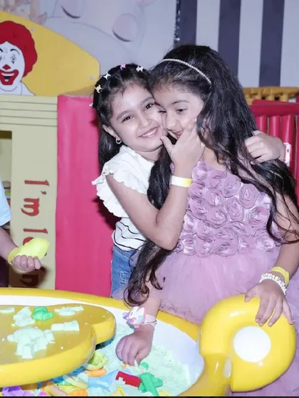 Two friends share a hug while playing at the sand table.