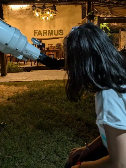 A guest looking through the telescope with the warm lights of our cafe in the background.