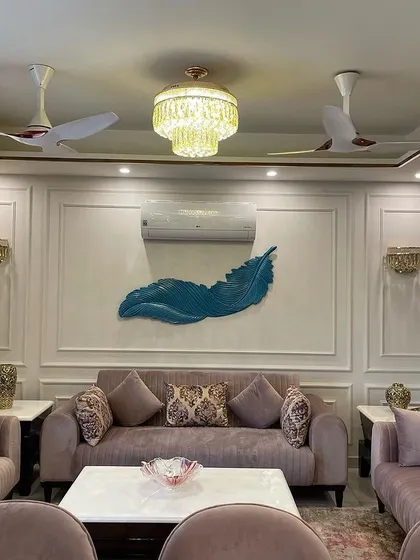 The living room is centered around this elegant seating arrangement with pastel sofas. A bold blue feather artwork serves as a striking focal point against the neutral wall with wainscoting, adding a unique artistic flair.