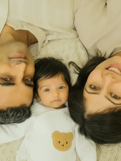 A fun and sweet family photo from above, with the baby nestled between mom and dad. Everyone's bright eyes and smiles make this shot so special.