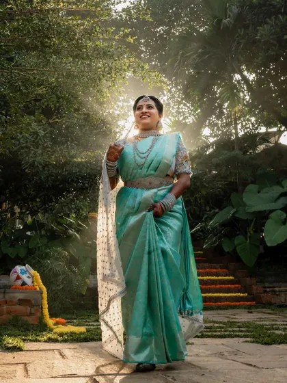 A sun-kissed bride in her beautiful turquoise saree. The natural light and lush green background make for a fresh and vibrant bridal portrait.