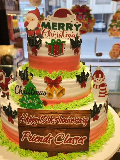 A festive three-tier cake perfect for a combined Christmas and anniversary celebration. It's decorated with edible holiday figures like Santa and a snowman.