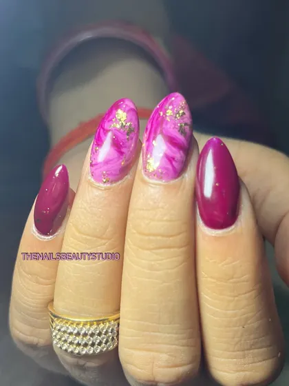 A vibrant pink and magenta set featuring a marble effect on two nails, accented with delicate gold foil.