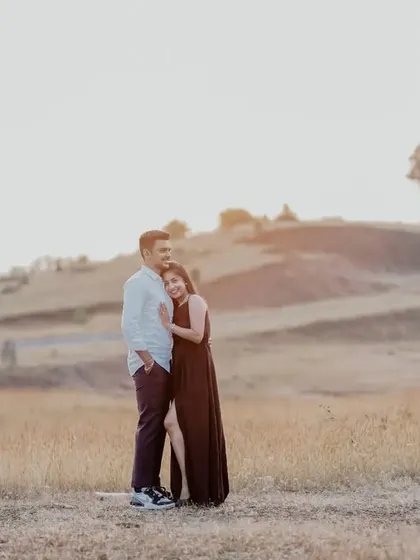 A sweet and relaxed portrait of the couple in a field at golden hour, creating a warm and romantic mood.