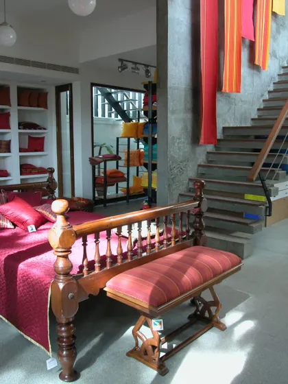 The interior of the Yamini store is designed to feel like a home, with products displayed in context. A traditional wooden bed is paired with the brand's textiles, allowing customers to visualize how the products would look in their own space.