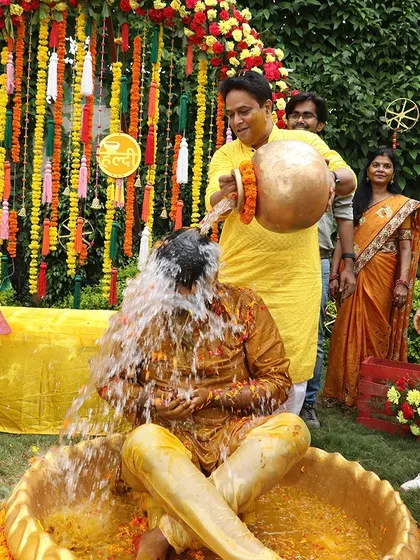 A playful moment during a Haldi ceremony, with the groom getting drenched in water.