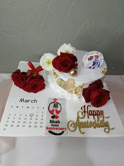 A full view of the calendar-themed anniversary cake, marking the special day with red roses.