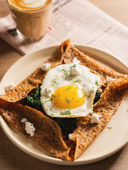 A savory crepe topped with a perfect sunny-side-up egg. The overhead angle and simple styling put the focus entirely on the delicious food.
