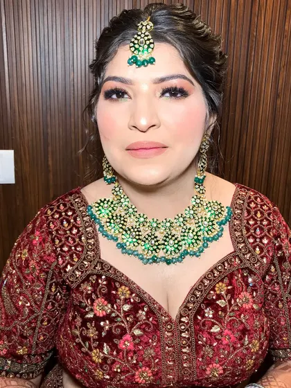 A frontal portrait showcasing the complete look, from the maang tikka to the stunning necklace.