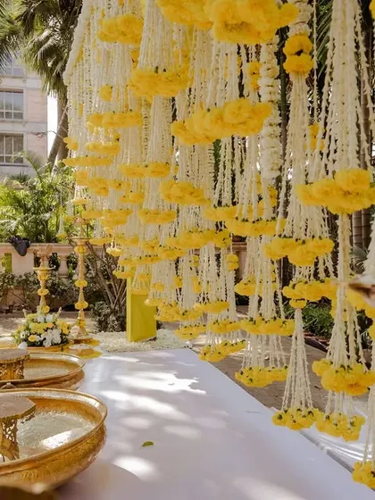A view of the traditional Haldi setup with brass urlis and hanging floral strings before the ceremony begins.