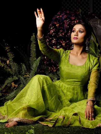 A magical, low-light outdoor shot of a model in a lime green Anarkali. The pose is ethereal, as if reaching for moonlight, creating a fairytale-like mood.