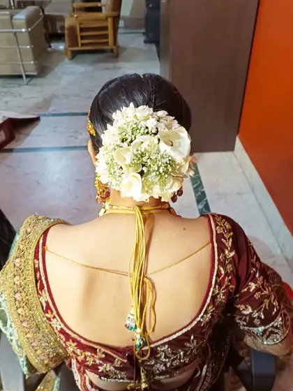 A full and beautiful bridal bun made with white roses and baby's breath. This is a classic choice that works perfectly with a traditional red or maroon wedding lehenga.