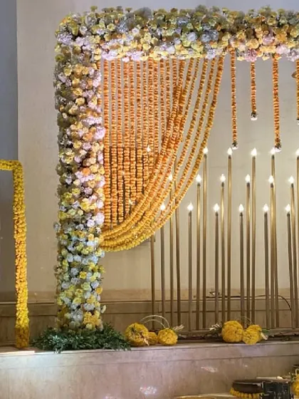 A personalized welcome sign framed with marigolds, set beside the illuminated floral entrance, adding a personal touch to the evening's decor.