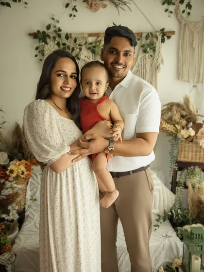 A picture-perfect family of three. This lifestyle portrait captures the family's bright smiles and easy connection in our warm, boho-chic studio setting.