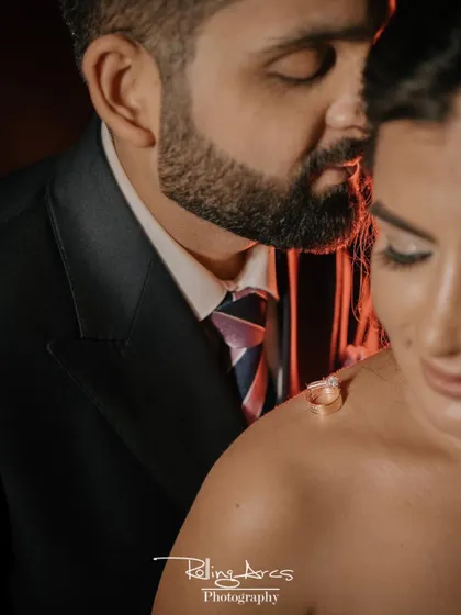 An artistic and intimate close-up focusing on the wedding rings placed on the bride's shoulder, symbolizing their union in a creative way.
