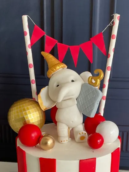 A close-up of the sweet, hand-sculpted elephant topper on the circus cake.