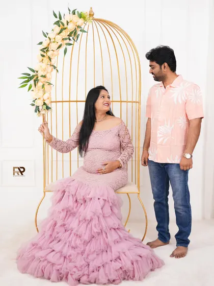 A happy moment with the dad-to-be. The couple shares a smile as the mom-to-be sits in the golden birdcage prop, looking lovely in her pink gown.