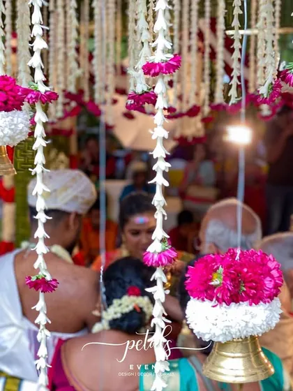 A close-up of the couple during the ceremony, with the focus on the hanging floral decorations and temple bells. This image captures the intimate and sacred nature of the moment.