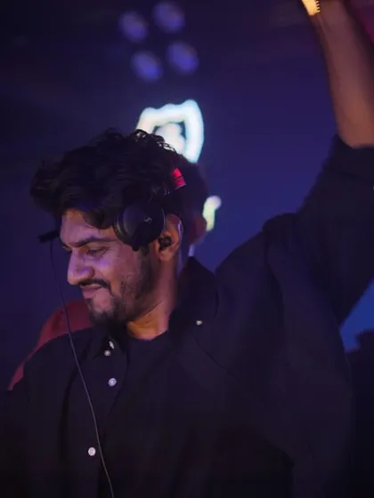 A side profile shot, arm raised, feeling the music. The dark, atmospheric lighting of the club sets the perfect mood.