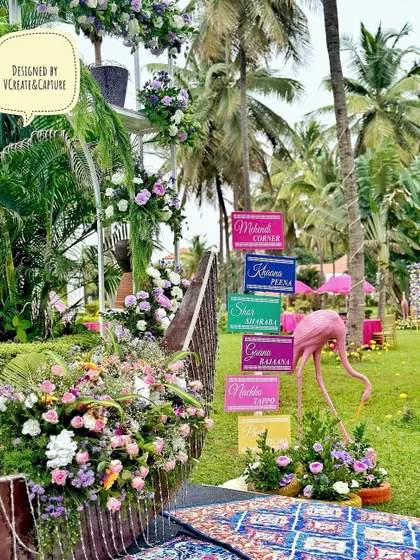 A fun and colorful sangeet photo corner with quirky signs, a pink flamingo, and bohemian-style rugs.