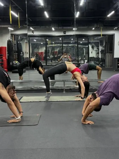 Students at Fitness First holding chakrasana together after an evening class.