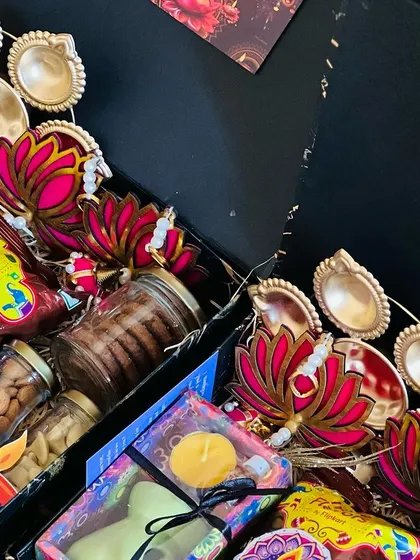 A close-up view of the contents of the black Diwali boxes, showing the vibrant colors of the snacks and decorative items.