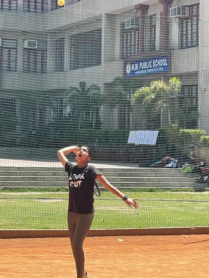 The follow-through of a serve, with our academy's home base, M.M. Public School, in the background.