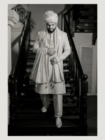 A handsome black and white portrait of the groom descending a staircase, captured in a classic, timeless style.