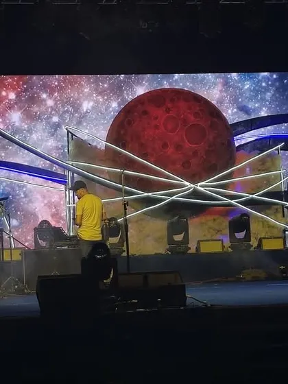 The band performing on the celestial sangeet stage. The backdrop of a blood moon on the LED screen adds a dramatic and powerful visual element to the live music performance.