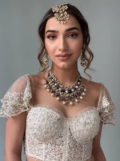 A modern take on a bridal updo. This textured, messy bun is accented with a stunning gold and pearl hair accessory, making it a perfect style for a contemporary bride's reception or cocktail event.