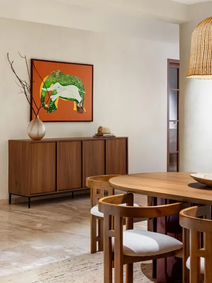 A modern dining room with a large wood credenza and a bold piece of art. This is a great example of how a simple piece of furniture can anchor a space.