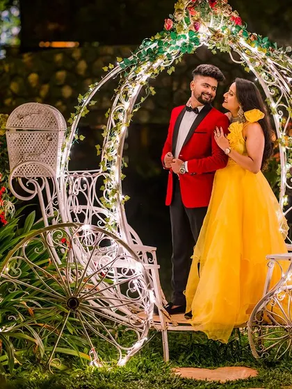 A true fairy-tale moment. The couple stands inside a Cinderella carriage adorned with twinkling lights, creating a magical and romantic portrait perfect for any love story.