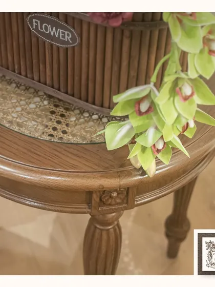 A close-up view of a side table with elegantly carved wooden legs. The table provides a perfect perch for a rustic flower basket, showcasing the beauty of natural wood grain.