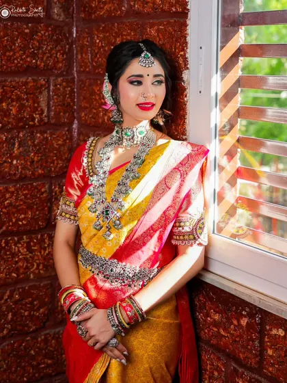 A beautiful portrait of a model by a window. The natural light illuminates her colorful saree and intricate silver jewelry, creating a soft and elegant image.