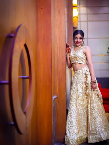 A full-length portrait of a woman in a stunning gold lehenga, posing confidently and showcasing her festive attire.