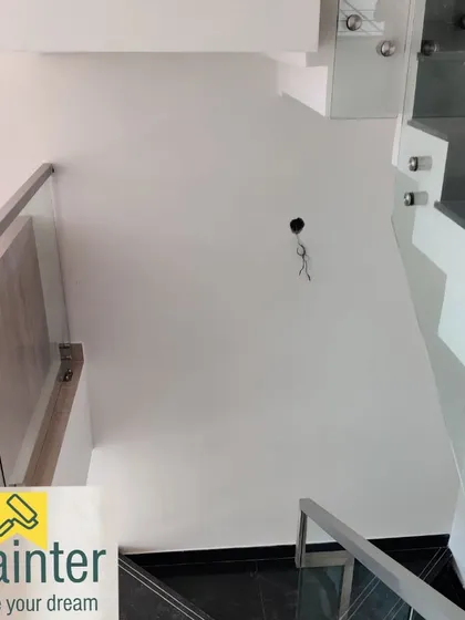 The same white stairwell, showing the crisp lines against the modern glass and steel railing.