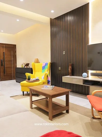 A contemporary living room with a playful mix of colors and textures. A bright yellow armchair and a bold red one add pops of color to the neutral sofa and dark wood paneling.