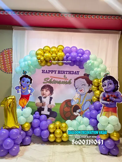 A charming Little Krishna theme for Shivansh's first birthday. This home setup includes a custom photo backdrop, character cutouts, and a balloon arch in purple, mint, and gold.