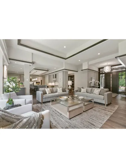 A spacious and elegant living room with a neutral color palette. We used layered rugs, glass coffee tables, and a mix of seating to create a sophisticated area for hosting guests.