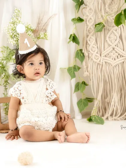 A quiet, observant moment during a busy first birthday shoot. The simple props and neutral tones keep the focus on her.