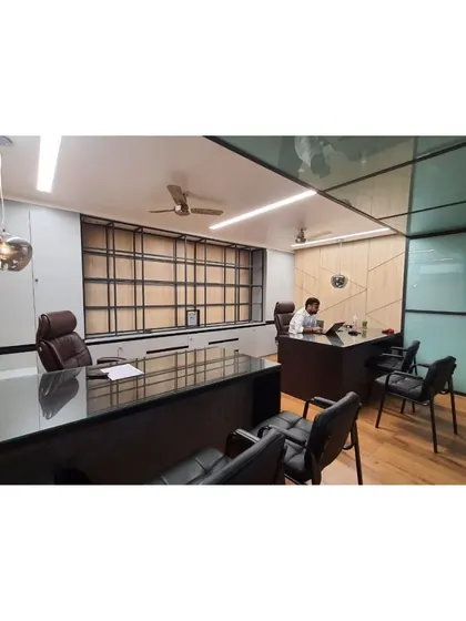 Another angle of the minimalist office cabin for Mr. Vishesh. The design includes a glass partition to maintain a sense of openness, while the wooden flooring and paneled walls add warmth and texture to the professional environment.