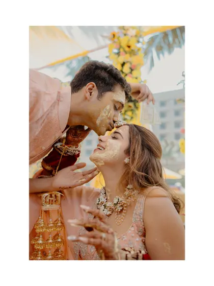 A tender forehead kiss amidst the Haldi celebration. It's a quiet moment of affection in the middle of a high-energy event.