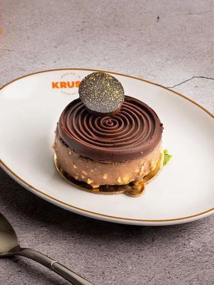 A beautifully crafted chocolate pastry with a spiral top and a crunchy base. I love experimenting with textures and shapes to create new and exciting desserts.
