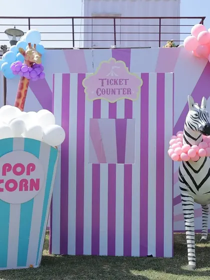 A fun and oversized popcorn box and ticket counter setup for an outdoor carnival. The life-sized zebra prop adds an extra element of surprise and delight for the kids.