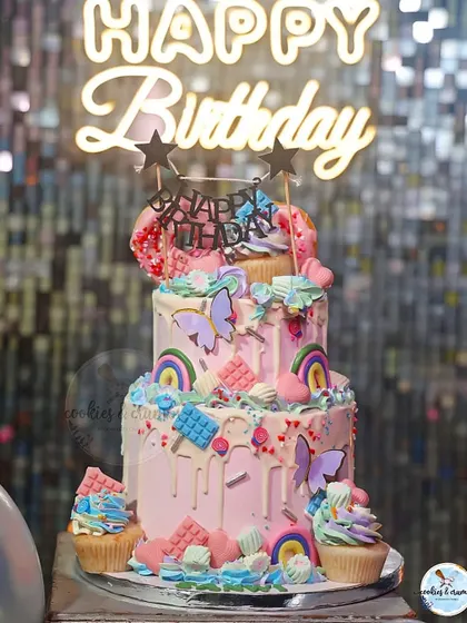A two-tiered cake for a Candyland themed party. The bottom tier was Chocolate Raspberry and the top was Fresh Fruit, all decorated with candy-colored drips, rainbows, and sweets.