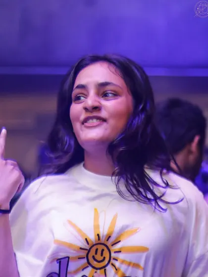 A woman in a 'sunshine' t-shirt, pointing and smiling. She's bringing the light to the party.