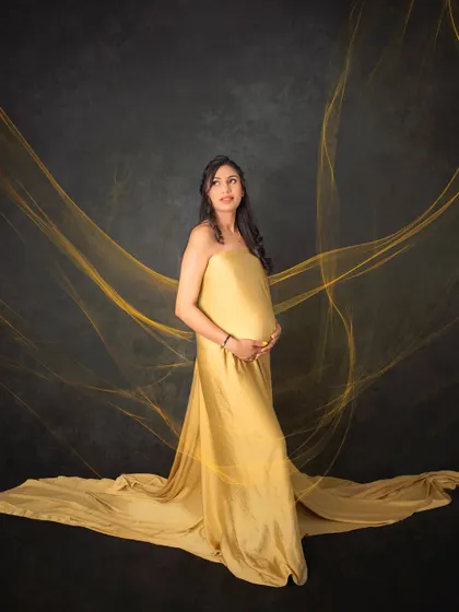 A truly radiant solo portrait of a mom-to-be. The flowing golden gown and ethereal fabric effects create a powerful and elegant image, celebrating the strength and beauty of motherhood.