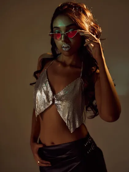 A moody, high-fashion shot with a "hot and unbothered" vibe. I styled a silver chainmail top with crystal-studded lips and colored sunglasses, using low-key lighting to create a glamorous and edgy feel.